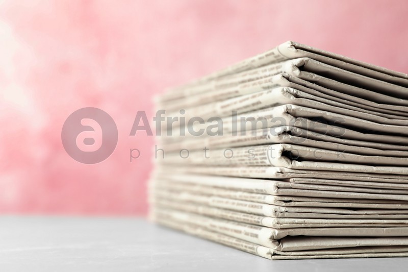 Stack of newspapers on pink background, closeup. Journalist's work