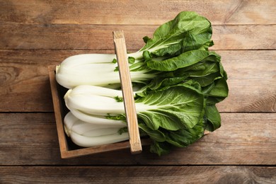 Fresh green pak choy cabbages in crate on wooden table, top view