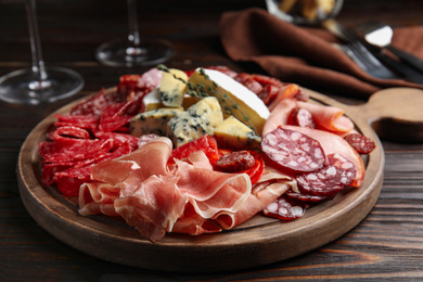 Tasty prosciutto with other delicacies served on wooden table