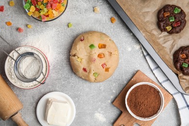 Unbaked cookies with candied fruits on grey table, flat lay