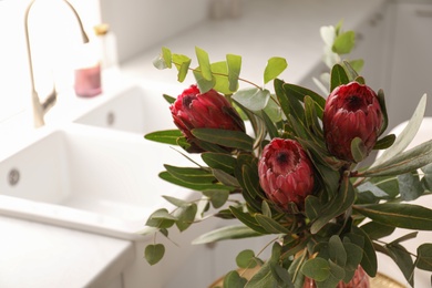 Photo of Bouquet of beautiful protea flowers in kitchen, closeup. Interior design