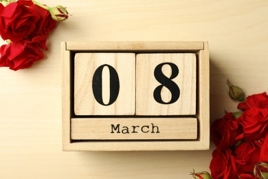 Block calendar with date 8th of March and roses on wooden background, flat lay. International Women's Day