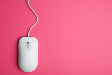 Wired computer mouse on pink background, top view. Space for text