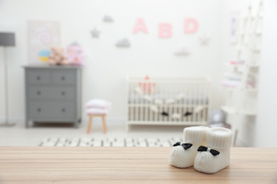 Small baby booties on wooden table in room. Space for text