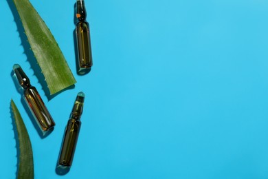 Pharmaceutical ampoules with medication and aloe leaves on light blue background, flat lay. Space for text