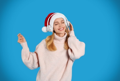 Happy woman with headphones on blue background. Christmas music