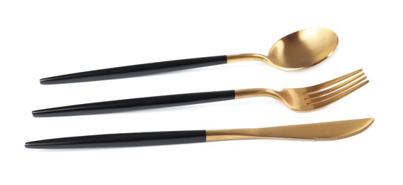 Photo of New golden cutlery with black handles on white background