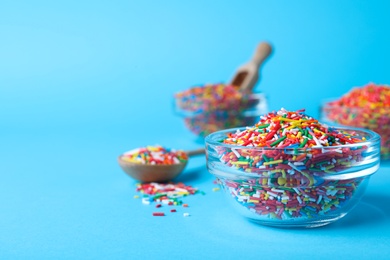 Colorful sprinkles in bowl on light blue background, space for text. Confectionery decor