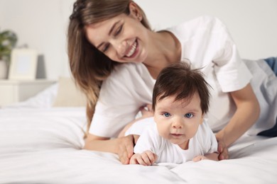Photo of Cute little baby and mother on cosy bed in room