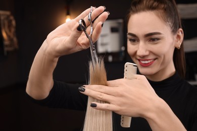 Professional hairdresser cutting woman's hair in salon, focus on hands