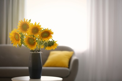 Vase with beautiful yellow sunflowers on table in room, space for text
