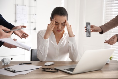 Stressed and tired young woman surrounded by colleagues at workplace, closeup