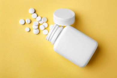 Bottle with different pills on color background, flat lay