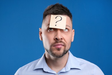 Emotional man with question mark on blue background