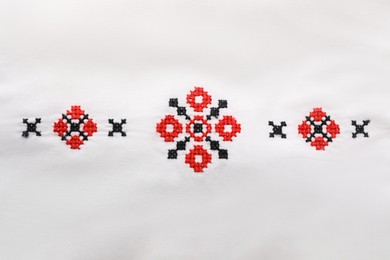 Beautiful red Ukrainian national embroidery on white fabric, top view