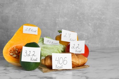 Photo of Food products with calorific value tags on white marble table. Weight loss concept