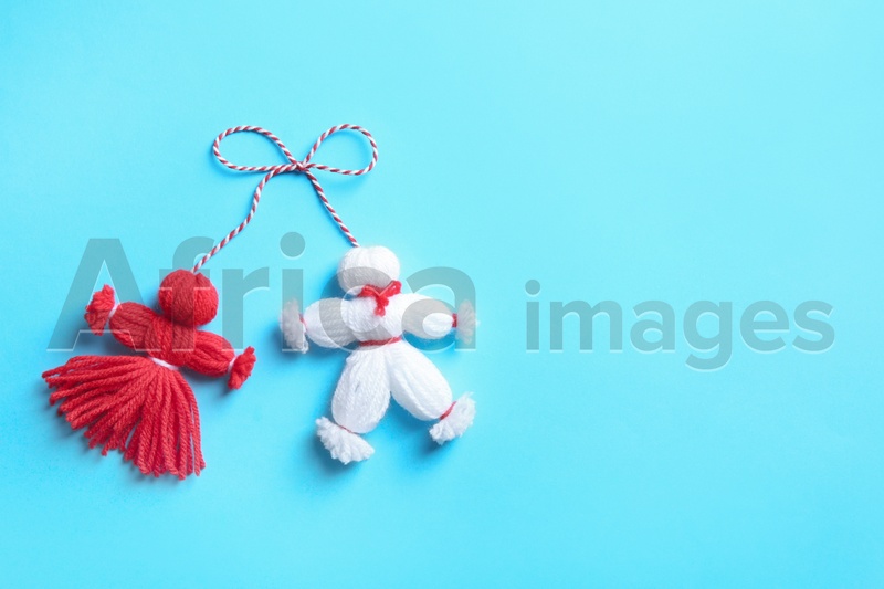 Traditional martisor shaped as man and woman on light blue background, top view with space for text. Beginning of spring celebration
