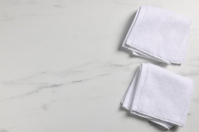 Photo of Clean folded towels on white marble table, flat lay. Space for text