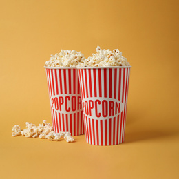 Delicious popcorn in paper cups on yellow background