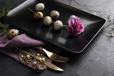 Festive Easter table setting with quail eggs and floral decoration on dark background, closeup