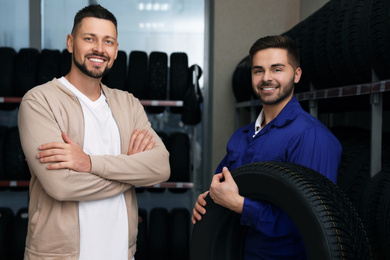 Mechanic helping client to choose car tire in auto store