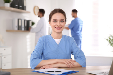 Portrait of female doctor at table in modern clinic