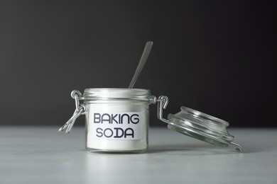 Open jar with baking soda on grey table