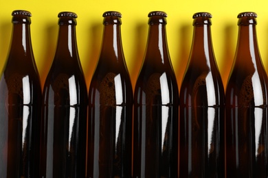 Photo of Bottles of beer on yellow background, flat lay