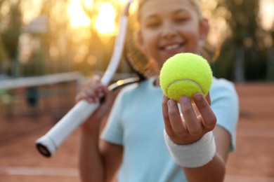 Cute little girl with tennis racket outdoors, focus on ball