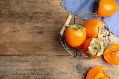 Delicious fresh persimmons on wooden table, flat lay. Space for text