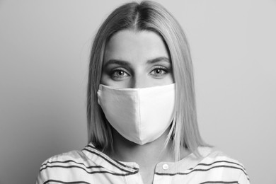 Woman wearing medical face mask on light background. Black and white photography