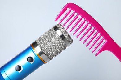 Making ASMR sounds with microphone and comb on grey background, closeup