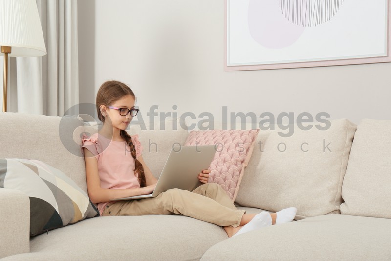 Girl with laptop on sofa at home