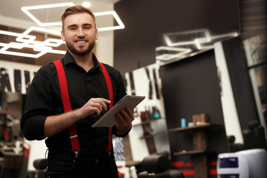 Young business owner with tablet in barber shop