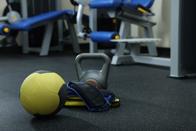 Yellow medicine ball, kettlebell and weighting agents on floor in gym, space for text