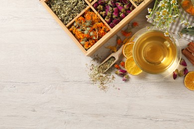 Freshly brewed tea and dried herbs on white wooden table, flat lay. Space for text