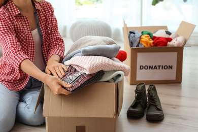 Woman packing clothes into donation box at home