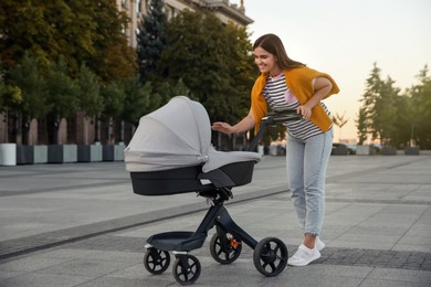 Young mother walking with her baby in stroller outdoors