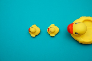 Rubber toy ducks on teal background, flat lay