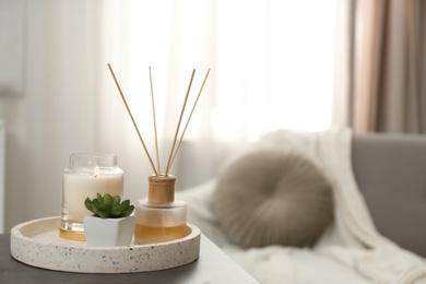 Air reed freshener, candle and plant on table in room, space for text