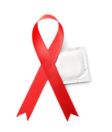 Red ribbon and condom isolated on white, top view. AIDS disease awareness