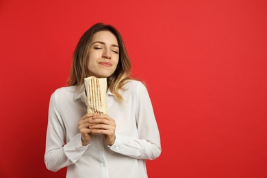 Photo of Young woman with delicious shawarma on red background, space for text