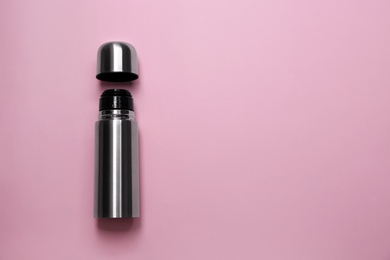 Stainless steel thermos on pink background, top view. Space for text