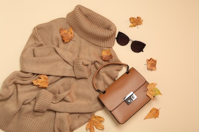 Flat lay composition with sweater and dry leaves on beige background. Autumn season