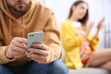 Man with smartphone ignoring his girlfriend at home, closeup. Relationship problems