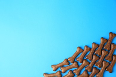 Photo of Bone shaped dog biscuits on light blue background, flat lay. Space for text