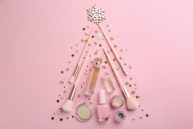 Christmas tree shape of decorative cosmetic products on pink background, flat lay\. Winter care