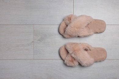 Pair of soft slippers on wooden floor, top view. Space for text