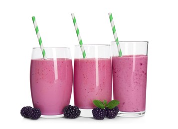 Glasses of blackberry smoothie with straws and berries on white background