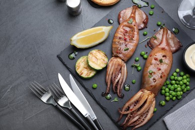 Photo of Tasty grilled squids served on black table, flat lay. Space for text